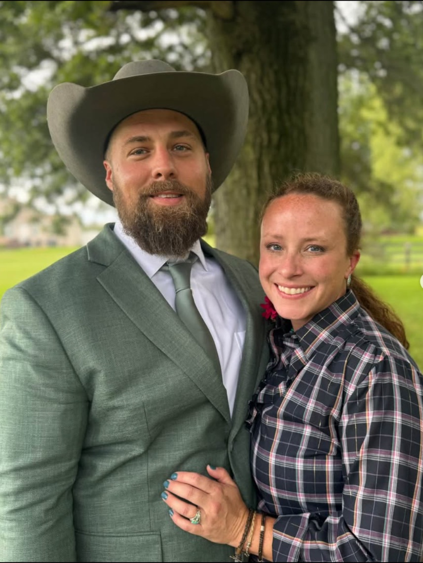 Emmie and her husband Steff, who run in-home dog boarding, under a tree on the farm